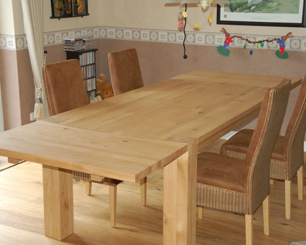 Esstisch aus hellem Massivholz mit Ansteckplatten und markanten Holzbeinen vom Tischler gefertigt.